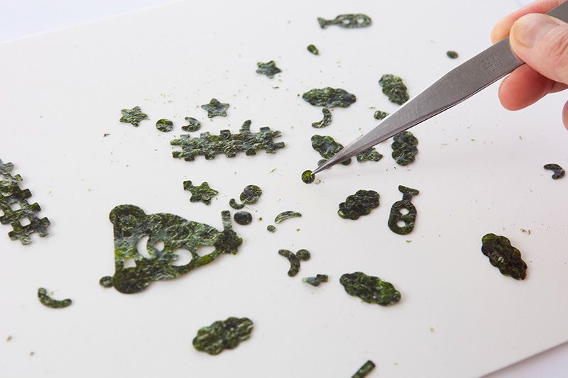 Pour les yeux du poulpe, nous avons utilisé des feuilles de nori prédécoupées en forme de rails de chemin de fer, parties de visage et autres. Si vous n’en avez pas à votre disposition, utilisez une feuille de nori ordinaire et découpez-la avec des ciseaux. Vous pouvez aussi vous servir de graines de sésame.