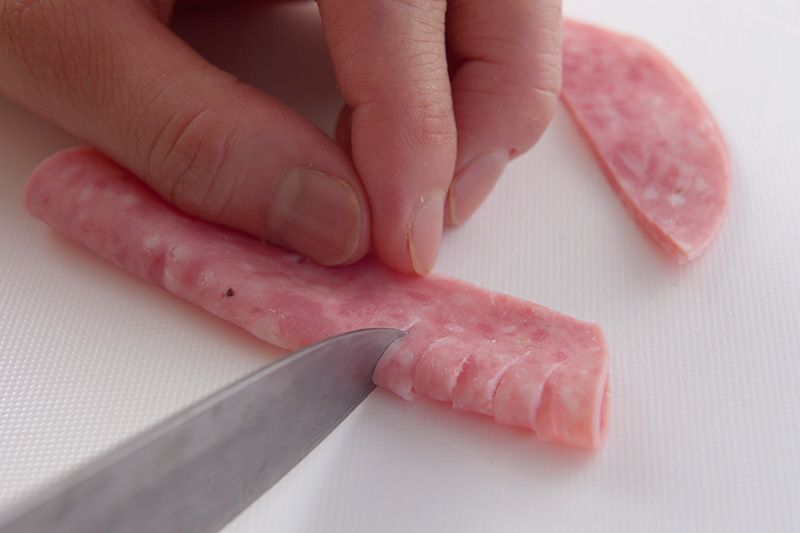 Pliez une petite tranche de jambon en deux et incisez-la du côté de la pliure.