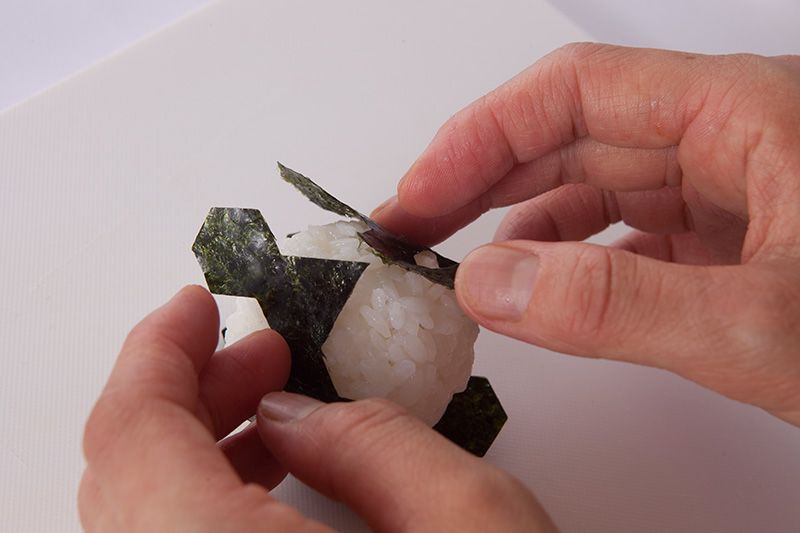 Enroulez la feuille d’algue tout autour de la boulette en veillant à ce que chaque pièce soit bien à sa place, comme dans un puzzle.