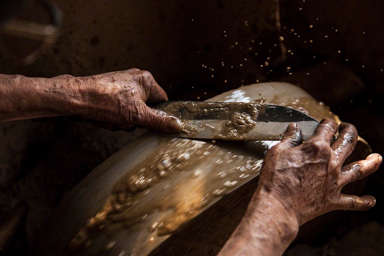 回転砥石で研ぐ熟練の手さばきに見惚れてしまう。愛知県設楽町の安藤義久さんの作業場で