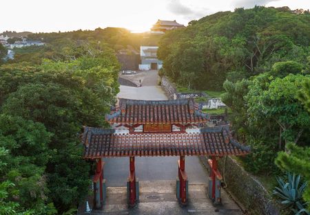 拆除修復工程遮蓋屏障後,顯露出身影的首里城正殿(後方)。前方為守禮門。攝於2025年11月7日,那霸市