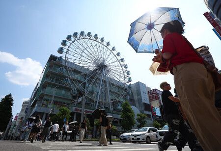 在酷熱天氣中撐陽傘行走的民眾。21日下午攝於名古屋市中區