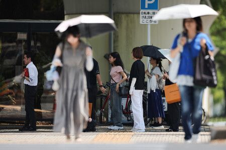 民眾在陰影處等待紅綠燈,以躲避高溫。21日下午攝於名古屋市中區