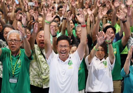 古謝玄太(前排中央)獲知確定當選沖繩縣知事後,與支持者一同慶祝。13日晚間攝於那霸市