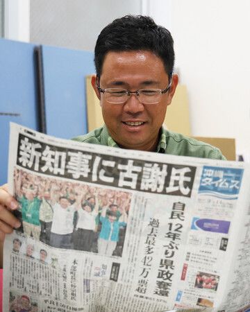 沖繩縣知事選舉落幕翌日,新當選的古謝玄太手持當地報紙露出笑容。14日上午攝於那霸市