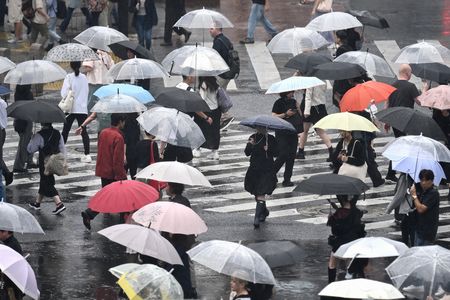 民眾20日冒雨行走在東京澀谷街頭。(法新社/時事通信)