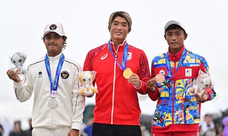 日本選手五十嵐卡諾亞(中)奪得亞運男子衝浪金牌後,手持獎牌露出笑容。29日攝於愛知縣大石海岸