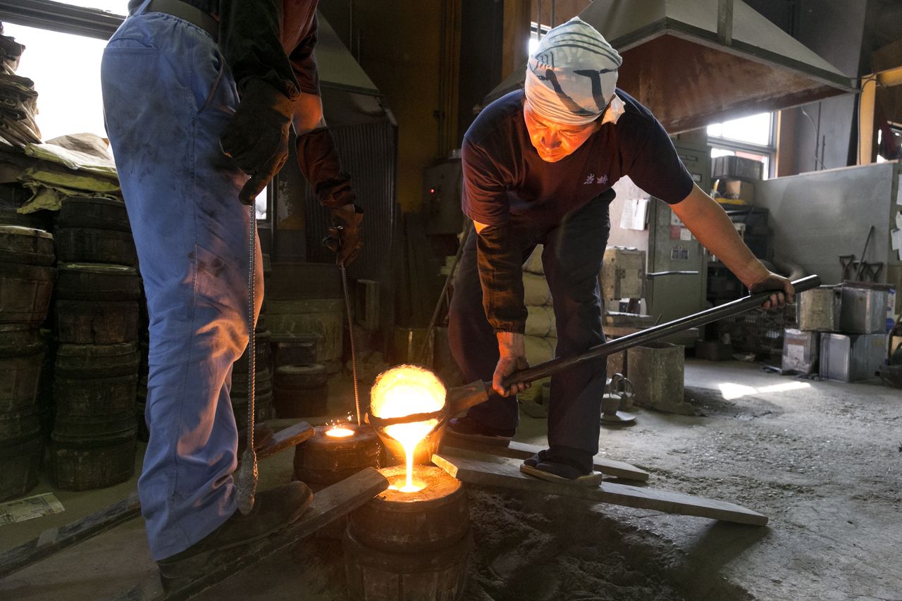 عملية الصب التقليدية. يُصنع قالب الصب من رمال نهرية ناعمة وطين، ثم يُملأ بحديد مصهور تبلغ حرارته 1,500 درجة مئوية. (إيواتشو)