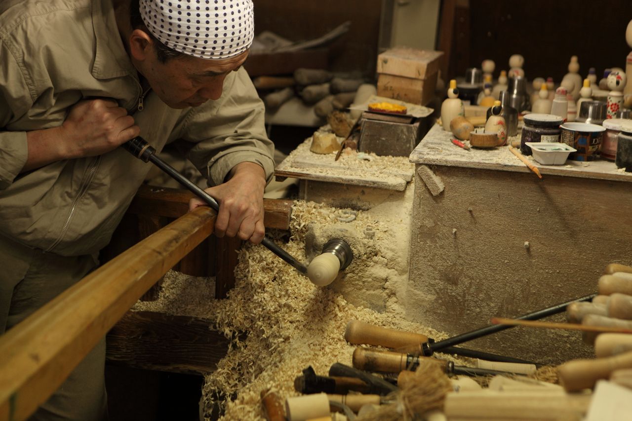 حفر قطعة خشب لصناعة كوكيشي في متجر ساكوراي كوكيشي. يستطيع للزوار هنا تجربة رسم تصميم على دمية كوكيشي الخاصة بهم.