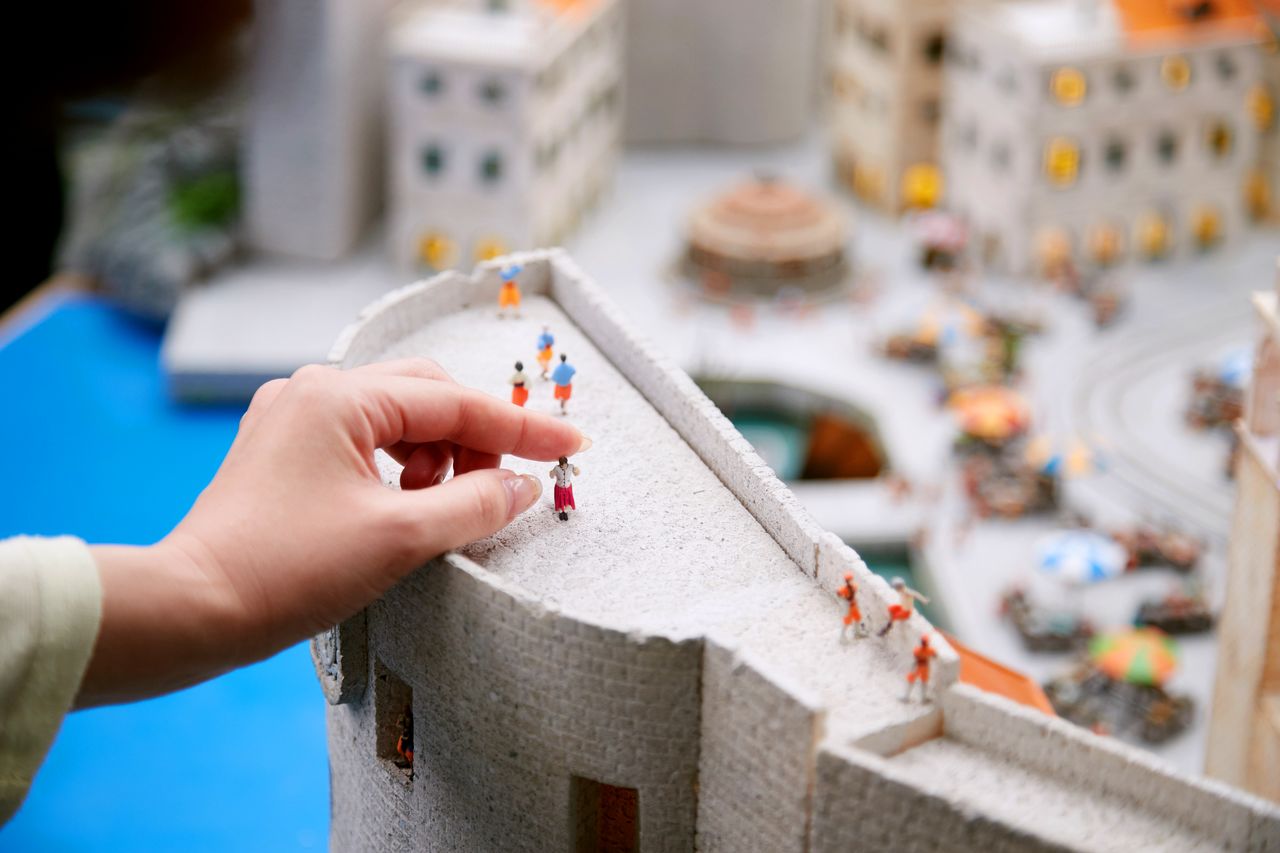 أحد الزوار في شخصيته المصغرة يتم وضعها على سطح أحد الأبنية. يمكنك من خلال تقنية المسح ثلاثي الأبعاد ارتداء زيك المفضل والوقوف بالشكل الذي يحلو لك. الصورة مقدمة من متنزه (سمول ورلدز).