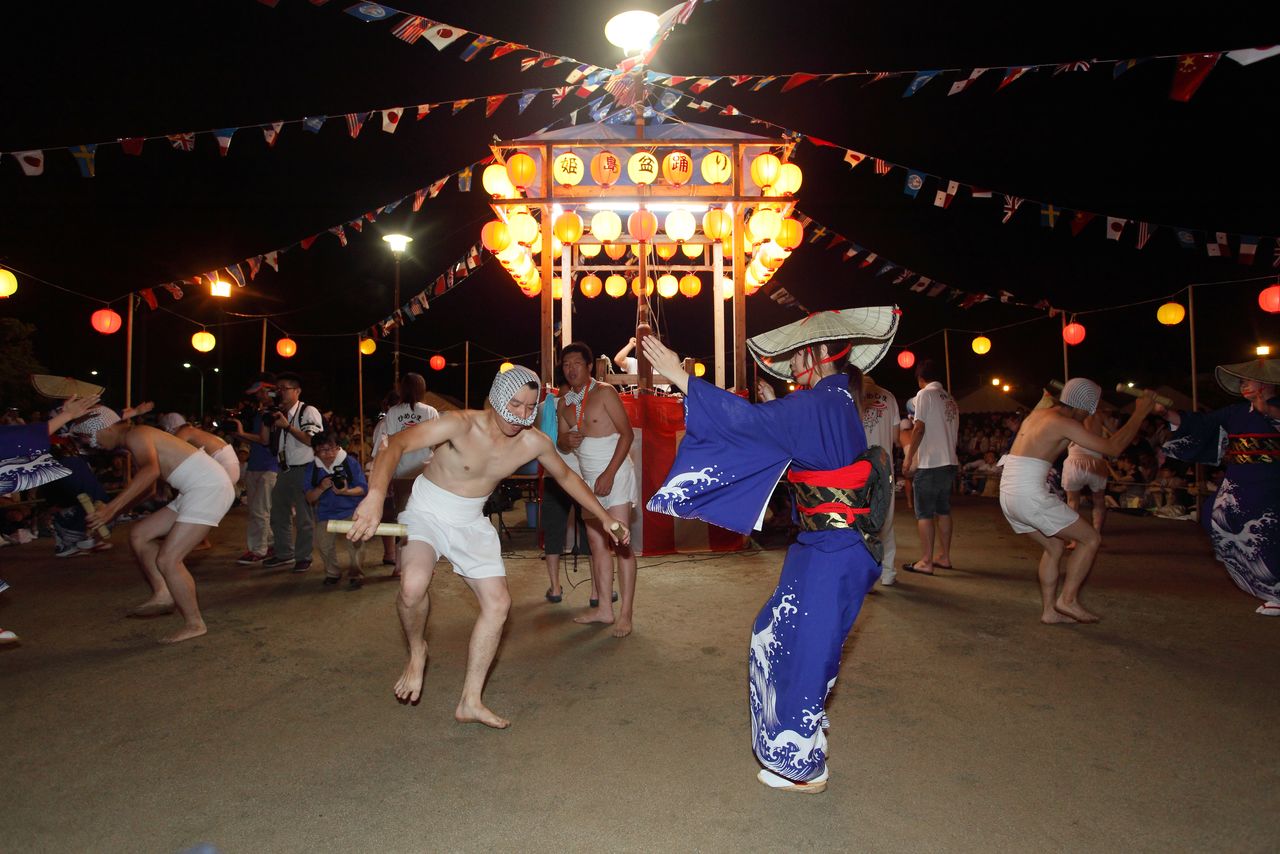  رقصة أيا أودوري، حيث يتقابل الرجال وهم عراة الصدور مع النساء ويرقصون وهم يحملون أعواد الخيزران (© مكتبة هاغا).