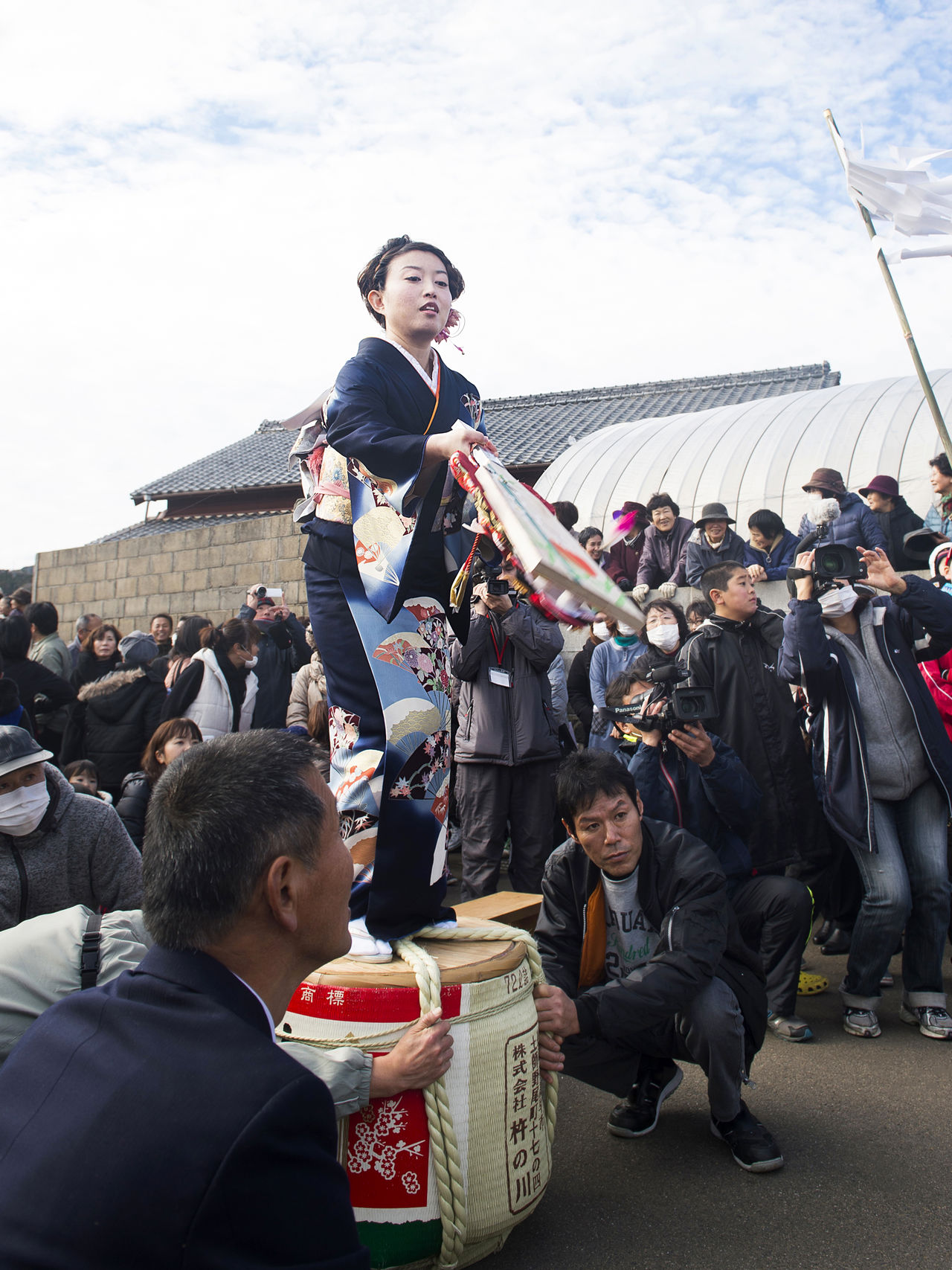 امرأة تقف على برميل للمشاركة في لعبة المضارب والريشة. مشاهد غريبة مثل هذه موجودة في كل مكان في مهرجان هيتوماتو.
