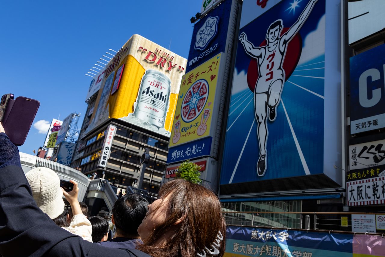 يزداد حماس الركاب مع الاقتراب من إعلان ”غليكو“ الشهير، حيث يتوقف المركب لالتقاط الصور (© Nippon.com)