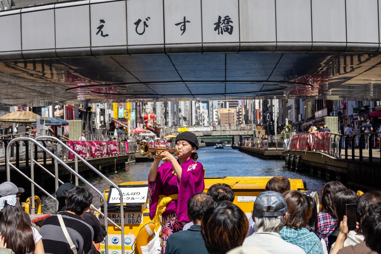 يقوم المرشد أو المرشدة بالعزف على البوق خلال المناسبات الخاصة. (© Nippon.com)