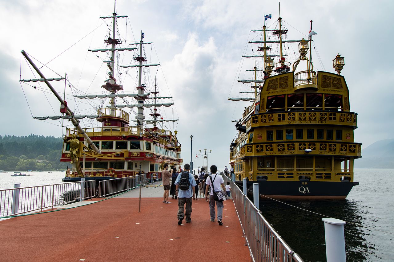 سياح بجانب سفينتي القراصنة ’’رويال اثنان‘‘ (على اليسار) والملكة أشينوكو الراسيتين في رصيف هاكوني ماتشي.