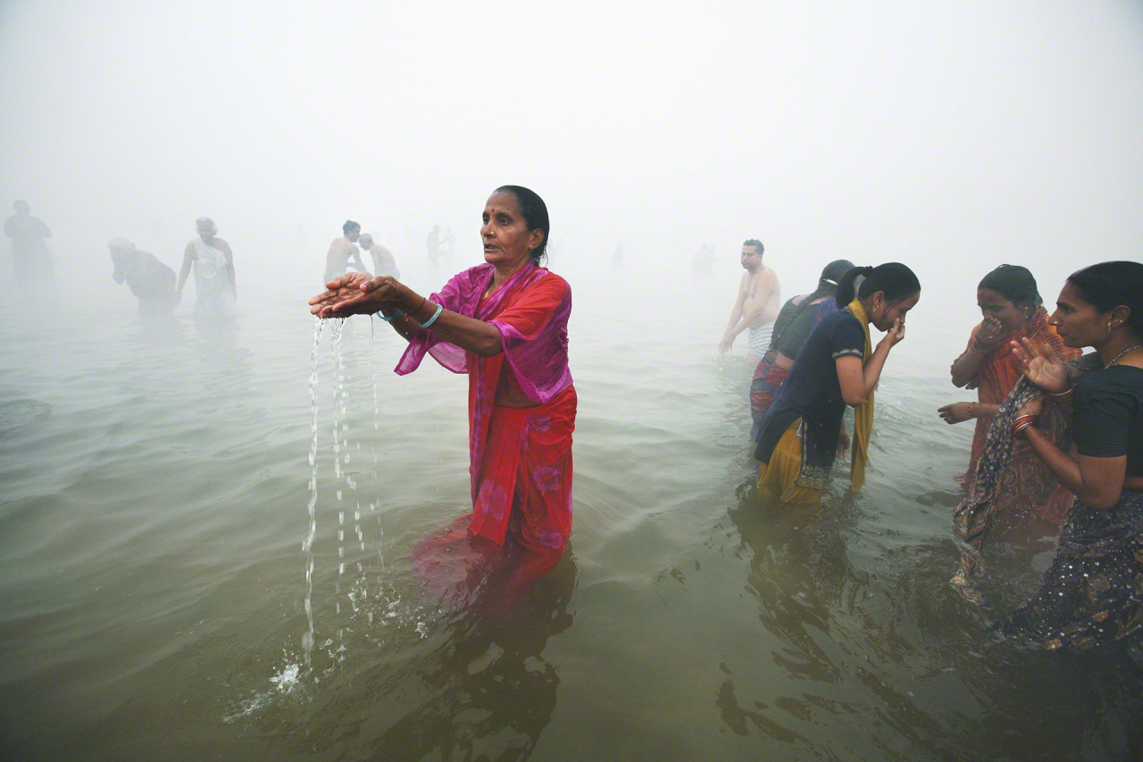 حجاج يغتسلون في كومبه ميلا (مهرجان هندوسي على النهر المقدس). تم التقاط الصورة في منطقة الله آباد المقدسة عند نقطة التقاء نهري الغانج وبراهمابوترا شمالي الهند في عام 2011. من كتاب ”الغانج“.