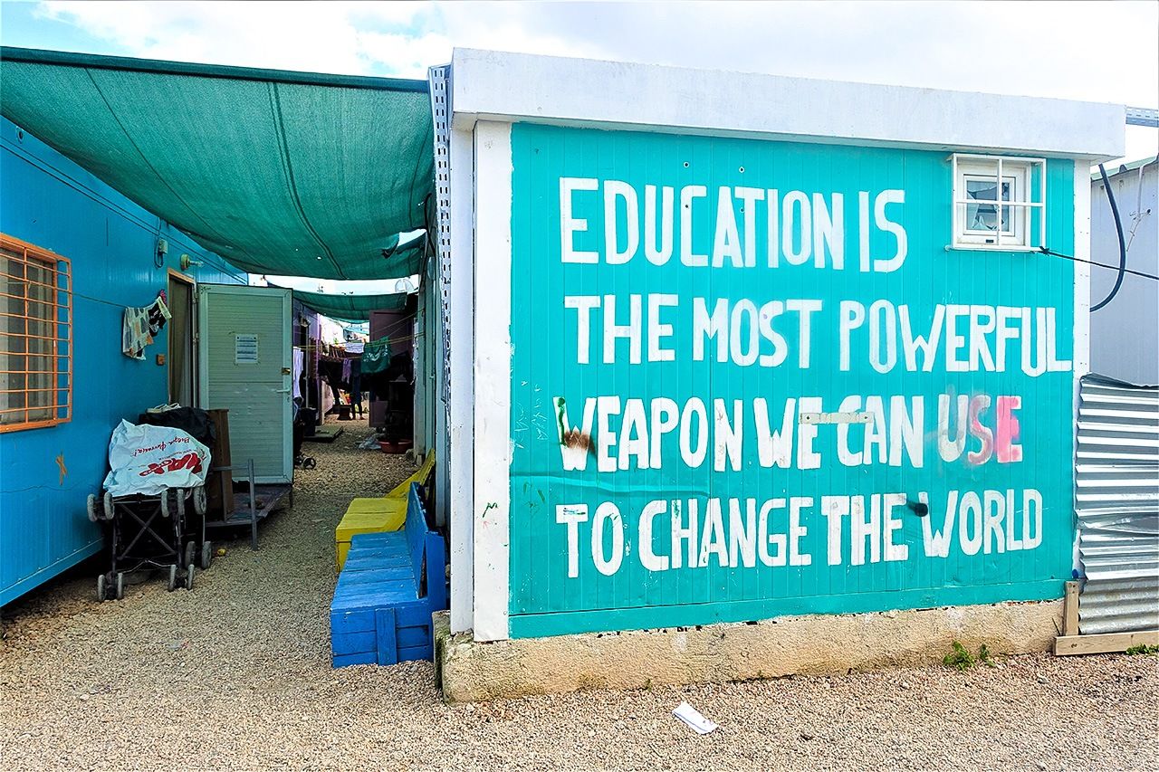 ”التعليم هو أقوى سلاح يمكن أن نستخدمه لتغيير العالم“ شعار على جدار أحد المساكن سابقة التجهيز داخل مخيم إليوناس  للاجئين.