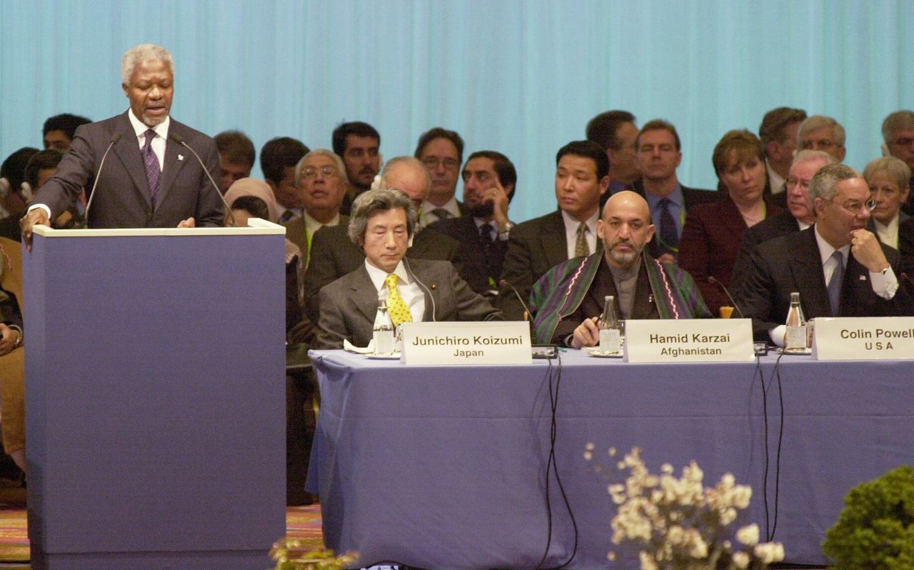 الأمين العام للأمم المتحدة كوفي عنان (أقصى اليسار) يلقي كلمة في مؤتمر الدول المانحة لإعادة إعمار أفغانستان. على اليمين رئيس الوزراء الياباني كويزومي جونئيتشيرو، ورئيس الحكومة المؤقتة لأفغانستان حامد كرزاي، ووزير الخارجية الأمريكي كولن باول (المناصب في ذلك الوقت، بتاريخ 21 /1/2002 في فندق تاكاناوا برينس في حي ميناتو في طوكيو) (جيجي برس)