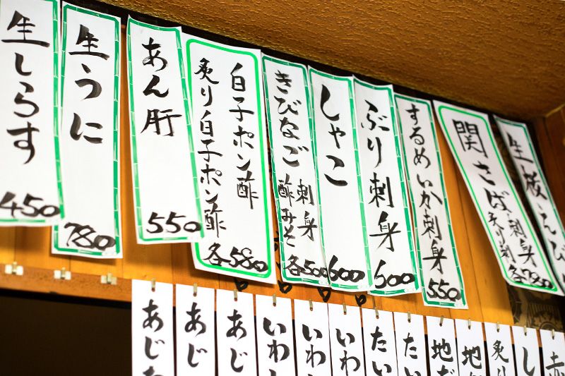 قائمة المأكولات والمشروبات معروضة على الحائط في حانة إزاكايا.