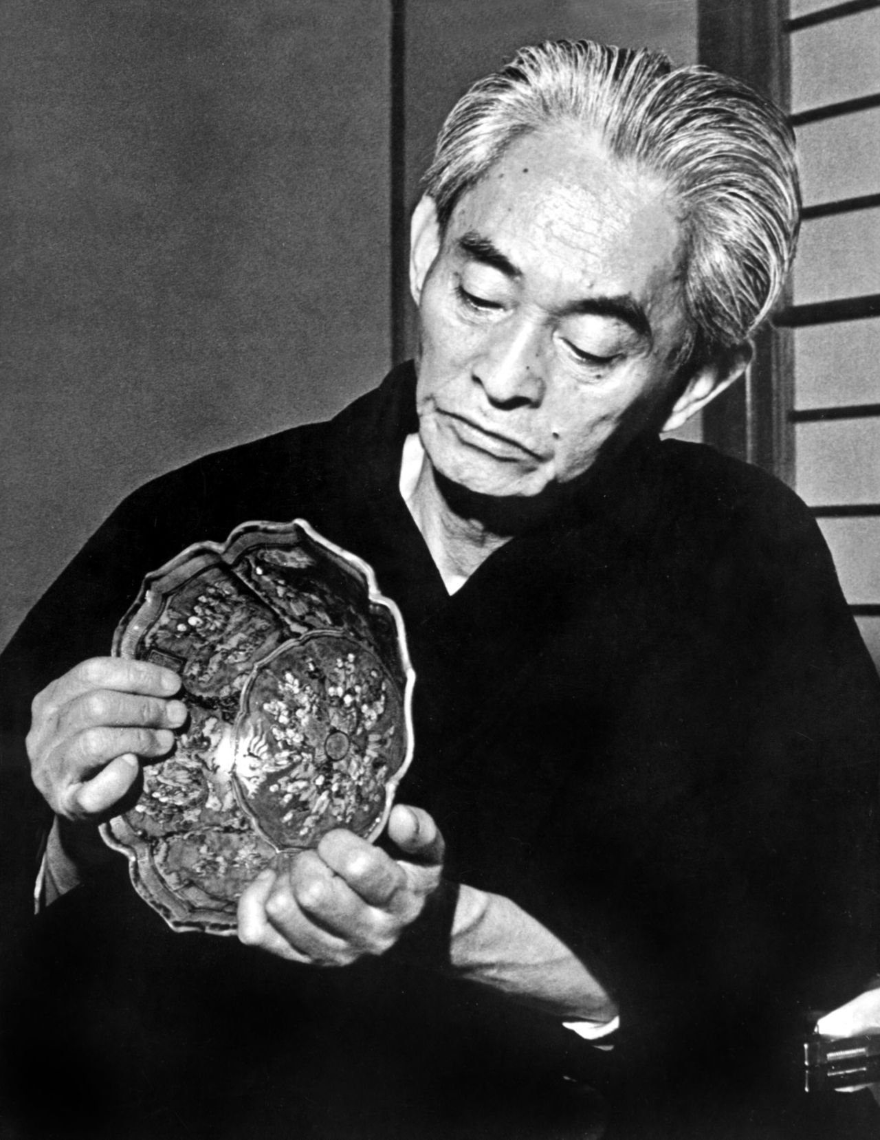 كاواباتا ياسوناري يتفحص عملا فنيا في منزله في زوشي بمحافظة كاناغاوا، في أبريل/نيسان عام 1972 (حقوق الصورة لأفلو).