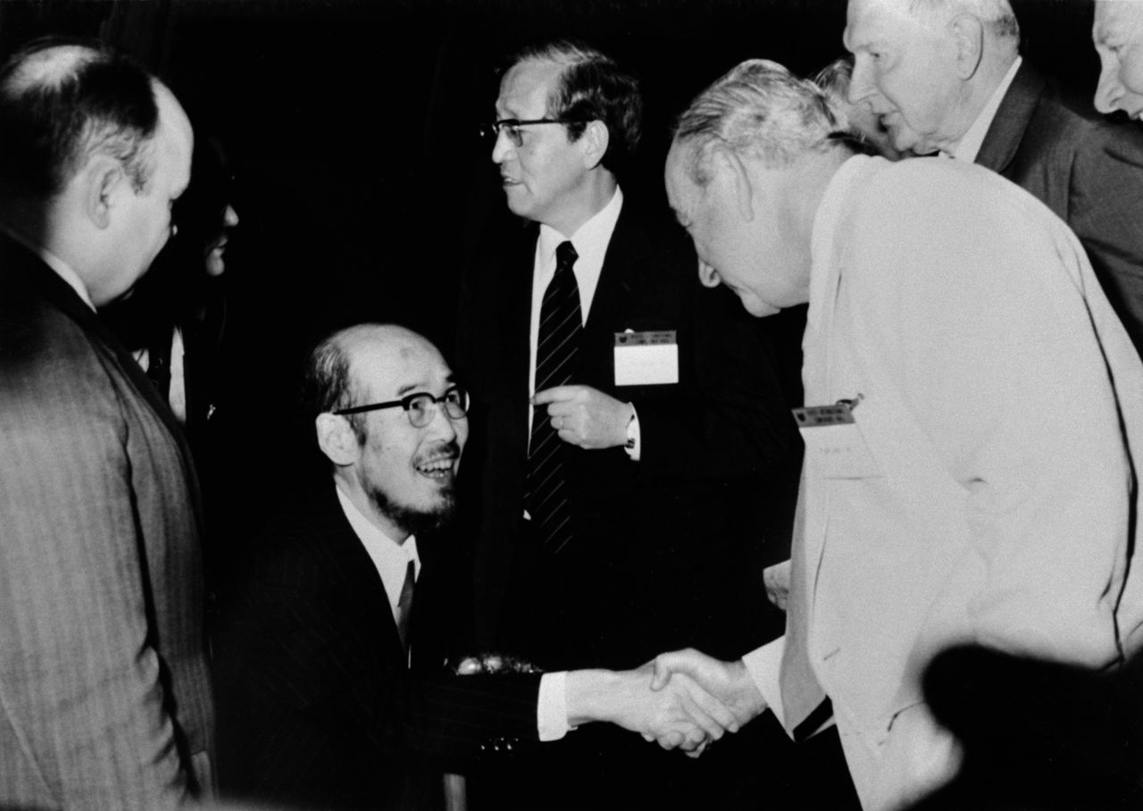 يوكاوا، جالسًا على كرسي متحرك، يحيي العلماء الأجانب في ندوة بوغواش عام 1975، وهي الأولى التي عُقدت في اليابان، في مركز مؤتمرات كيوتو الدولي. (جيجي برس)