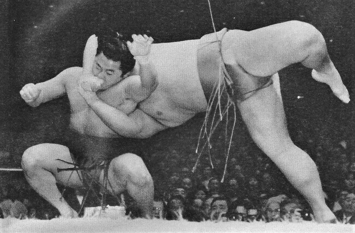 المباراة بين ماينوؤمي وتاكاتوريكي في بطولة يناير/كانون الثاني عام 1992. حاول ماينوؤمي (يسار) بعد أن دُفع نحو حافة الحلبة تأدية حركة إيزوري (الصورة بإذن من مجلة أوزومو).