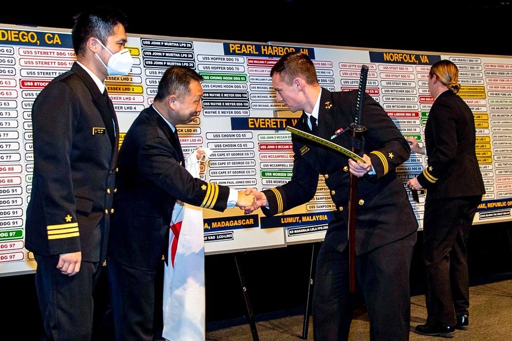 يقدم مائياما سيفًا احتفاليًا للدلالة على صداقة البحرية اليابانية الأمريكية لأول ضابط بحري يختار مهمة مقرها اليابان في فعالية، اختيار السفينة.