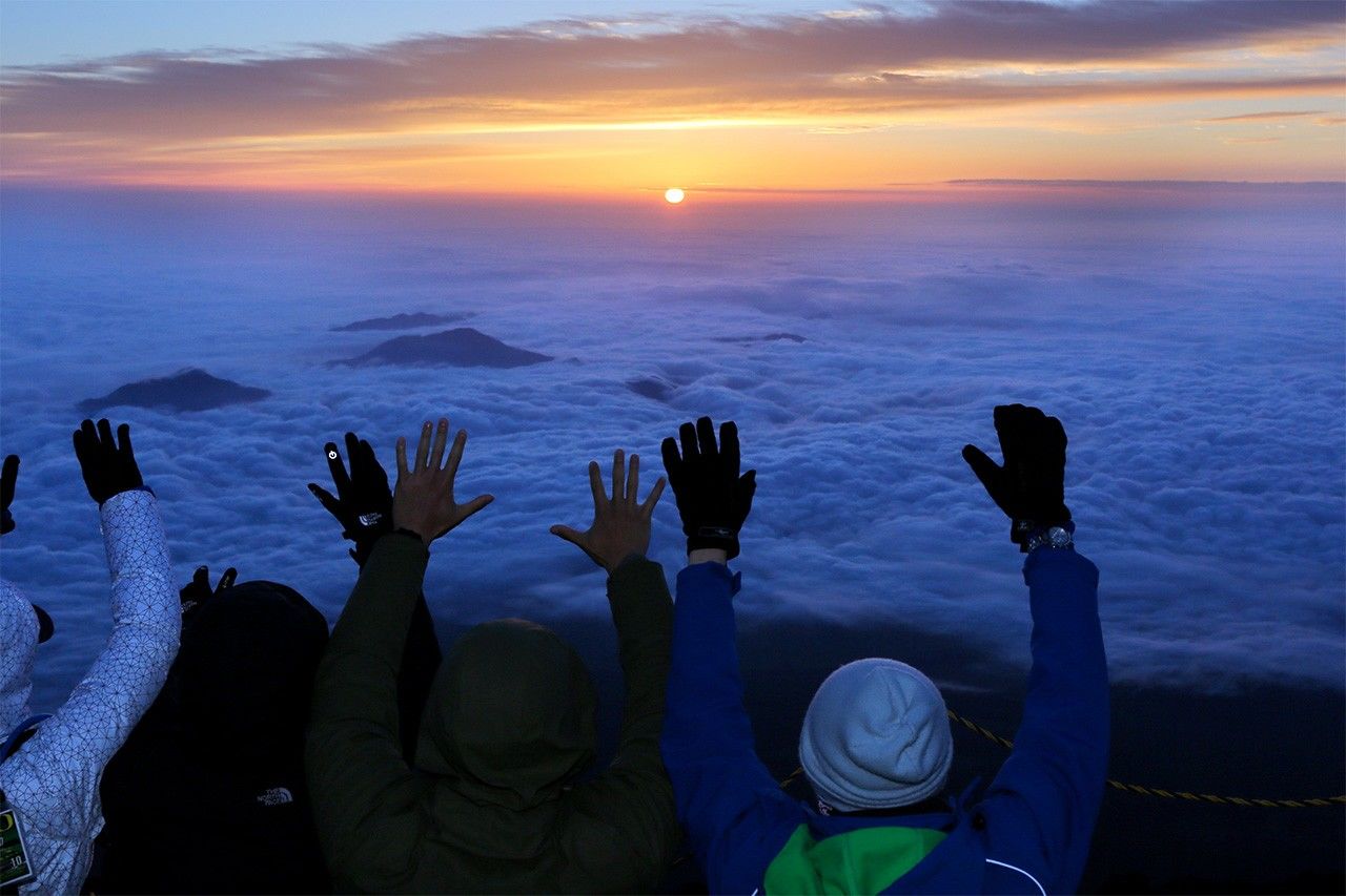 متسلقون يرحبون بإشراق الشمس من قمة جبل فوجي في 1 يوليو/تموز (© جيجي برس).