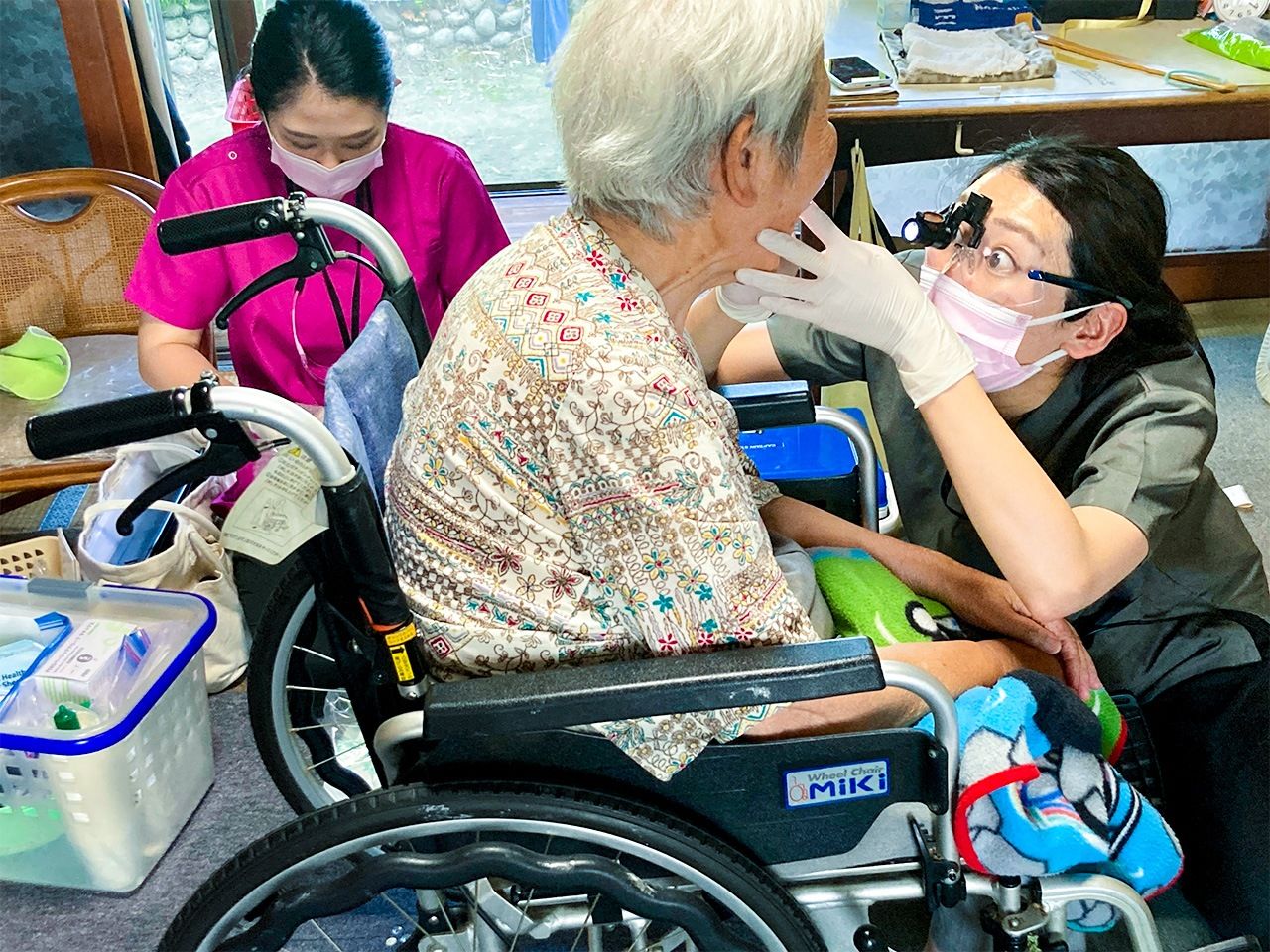 طبيبة الاسنان تتفحص أحد المرضى خلال زيارة منزلية. (© دايدو أتسوشي)