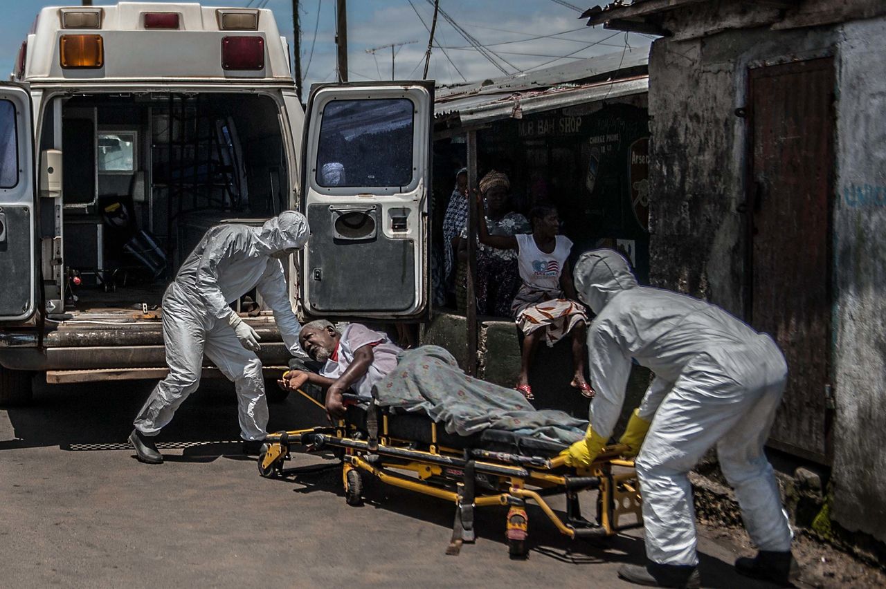 أطباء يرتدون ملابس واقية ويقومون بنقل مريض يشتبه في إصابته بفيروس الإيبولا إلى مستشفى في ليبيريا. التصوير بتاريخ 15/10/2014 (تصوير محمد الشامي/ وكالة الأناضول/ غيتي)