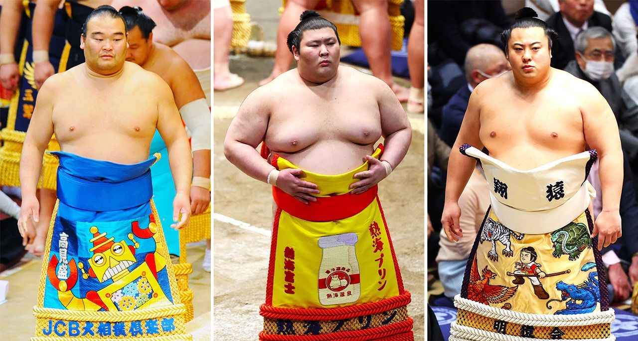من اليسار: المئزر الاحتفالي ˮكيشو ماواشي“ للمصارع ˮتاكاميزاكاري“ بتصميم مستنبط من لقبه ˮروبوكوب“. والمصارع ˮأتاميفوجي“ بتصميم يعرض نوعاً من حلوى الحليب المُحلى من مسقط رأسه؛ والمصارع ˮتوبيزارو“ بتصميم ˮمانكي كينغ“، وهي شخصية أسطورية، تعبر عن المصارع، حيث صغر القامة ولكنه قوي. (© جيجي برس)