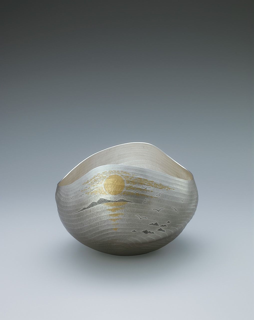 ”غروب الشمس“، إناء زهور فضي مصنوع باستخدام تقنية التشكيل بواسطة المطرقة. عُرض في معرض كوغاي الياباني التقليدي الثامن والستين (2021). (بإذن من جمعية كوغاي اليابانية)