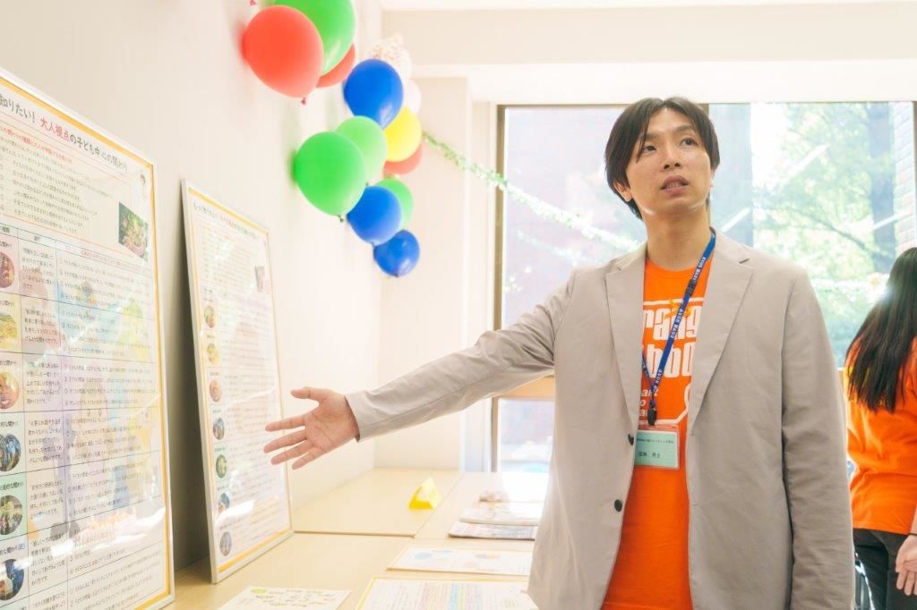 يشارك ساكاناشي معلومات حول حملة الشريط البرتقالي لحقوق الطفل، خلال فعالية نظمتها جامعة ميجيرو. (© غوتو إيري)