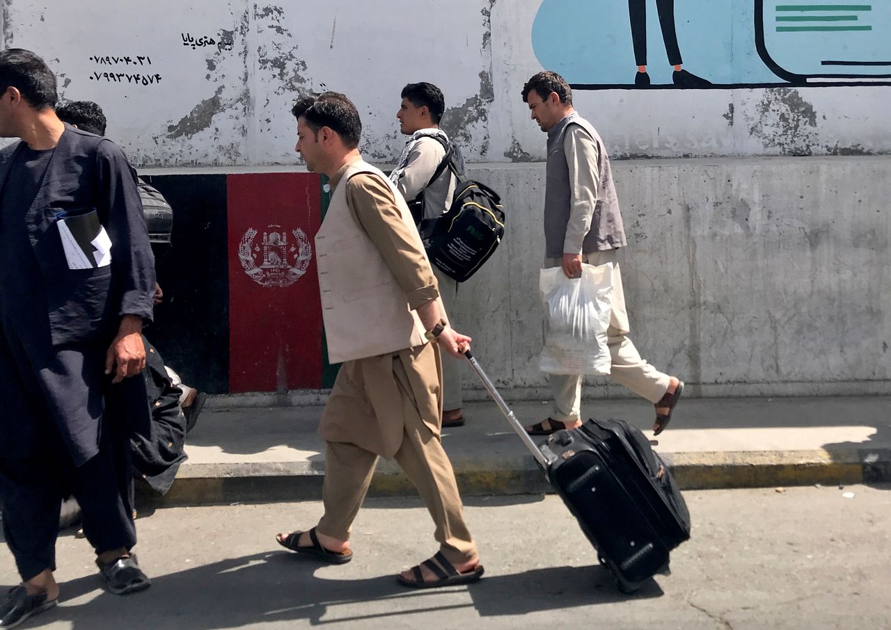 مسافرون أفغان يسيرون باتجاه المطار في كابول يوم الأحد - رويترز
