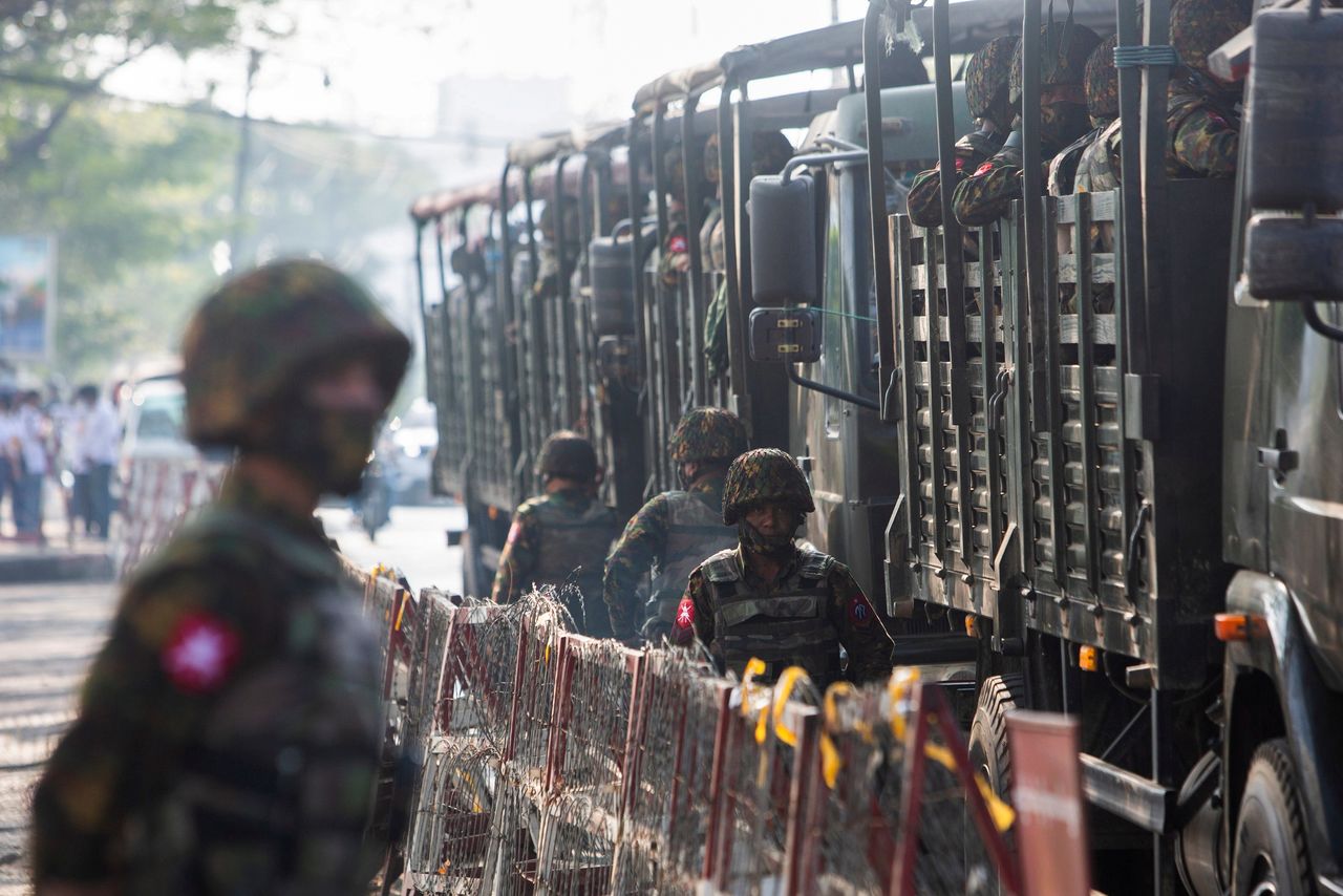 جنود من جيش ميانمار يقفون بالقرب من مركبات عسكرية أثناء تجمع أشخاص للاحتجاج على حكم المجلس العسكري في يانجون يوم 15 فبراير شباط 2021. صورة لرويترز.
