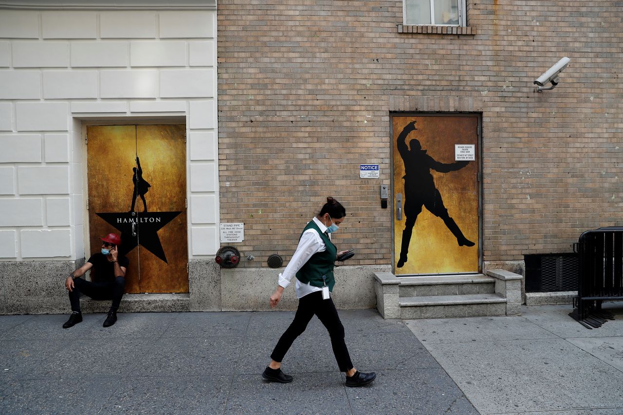 امرأة تسير مرتدية كمامة أمام اعلان لعرض مسرحي في برودواي في مانهاتن بنيويورك يوم الثلاثاء. تصوير:رويترز.