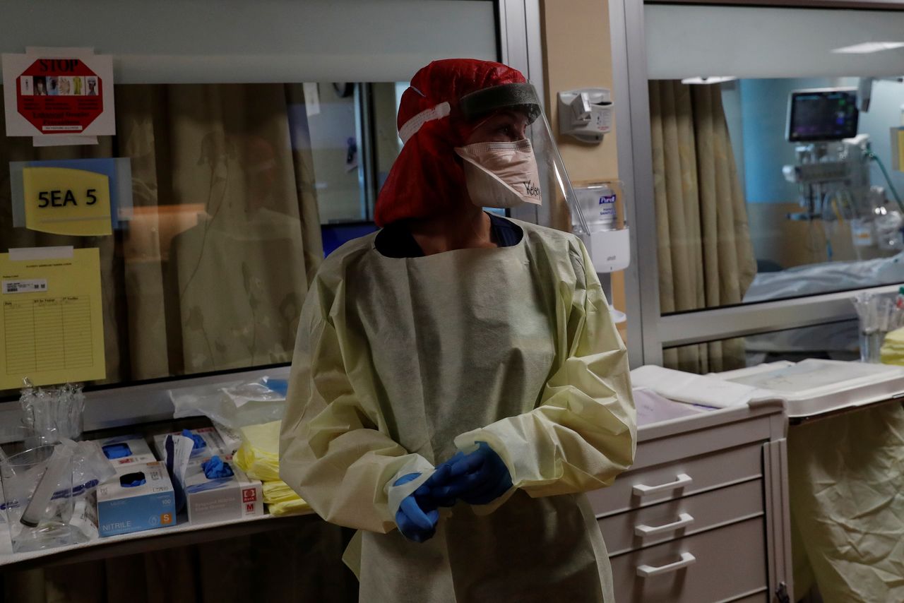 ممرضة قبل علاجها لمريض مصاب بفيروس كورونا في غرفة عزل بوحدة الرعاية الفائقة في مستشفى بساراسوتا في ولاية فلوريدا يوم الثلاثاء. تصوير:رويترز.