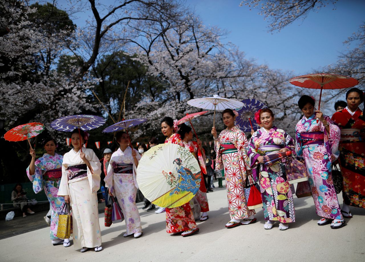  سائحون أجانب يرتدون زي الكيمونو ينظرون إلى أزهار الكرز المتفتحة في حديقة أوينو في طوكيو، اليابان، 22 مارس/ آذار 2020. تصوير: إيسي كاتو، رويترز.
