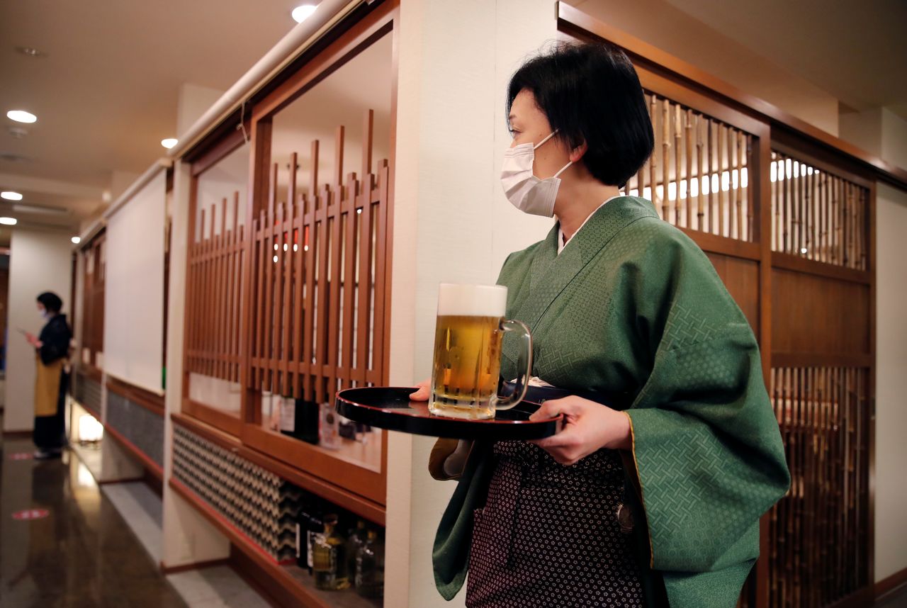 مديرة أحد مطاعم طوكيو تقدم مشروبا في طوكيو يوم الجمعة. تصوير: كيم كيونج هون - رويترز.