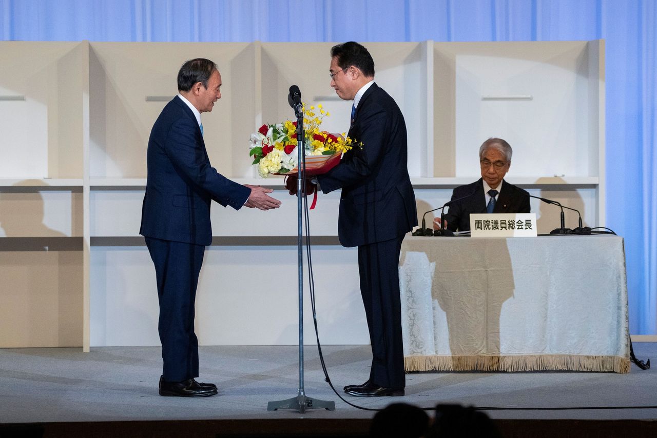 رئيس الوزراء الياباني المنتهية ولايته يوشيهيدي سوجا يتلقى باقة زهور من رئيس الوزراء‭ ‬المقبل فوميو كيشيدا في طوكيو يوم 29 سبتمبر أيلول 2021. صورة لرويترز من ممثل لوكالات الأنباء.