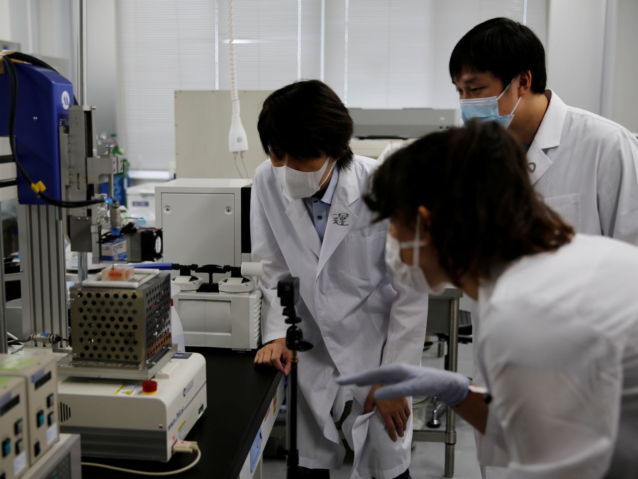 الأستاذ بجامعة أوساكا ميتسوساكي وزملاؤه الباحثون ينظرون إلى طابعة ثلاثية الأبعاد في مختبر بجامعة في سويتا، محافظة أوساكا، اليابان، 5 أكتوبر/ تشرين الأول 2021. تم التقاط الصورة في 5 أكتوبر/ تشرين الأول 2021. رويترز/ أكيرا توموشيغي.