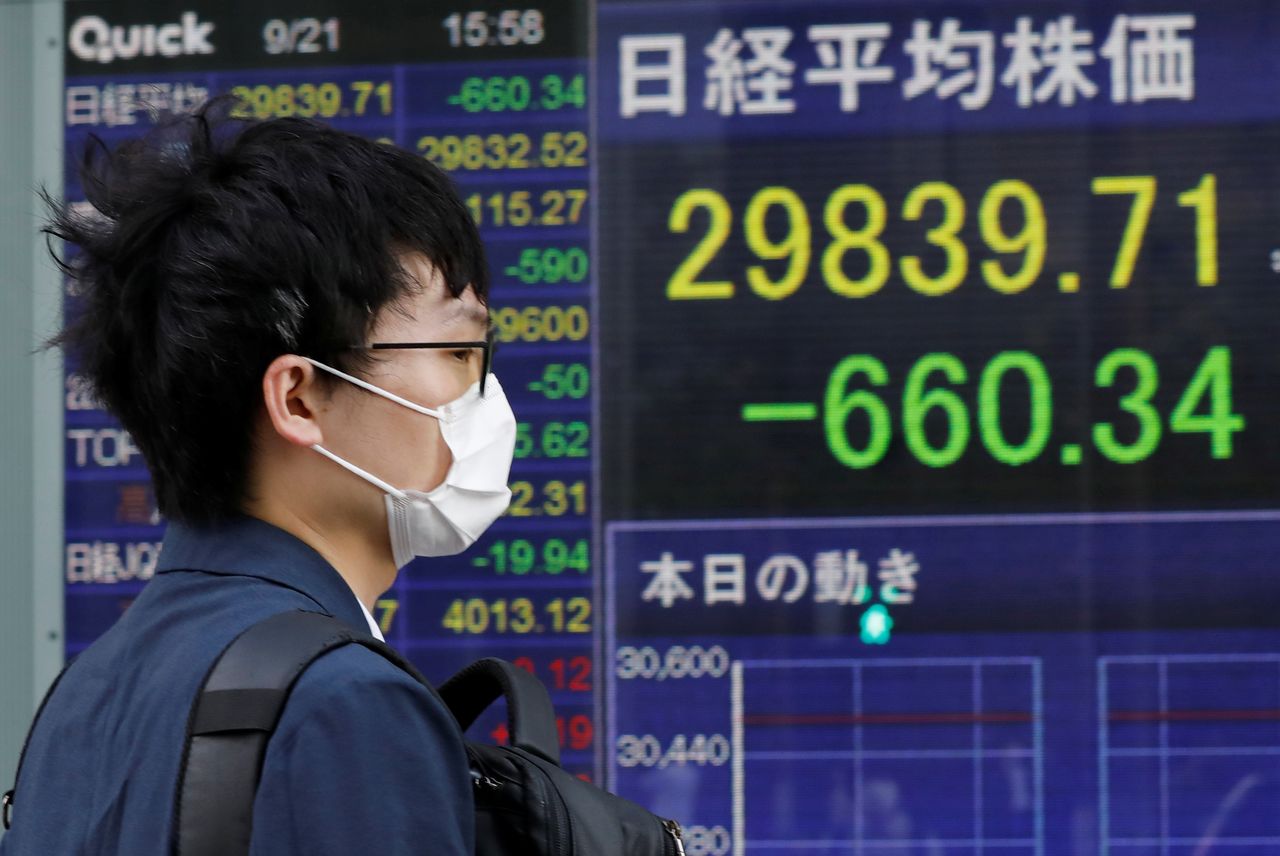 رجل يطالع شاشة الكترونية تعرض بيانات المؤشر نيكي في طوكيو يوم 21 سبتمبر ايلول 2021. تصوير: كيم كيونج هون - رويترز.