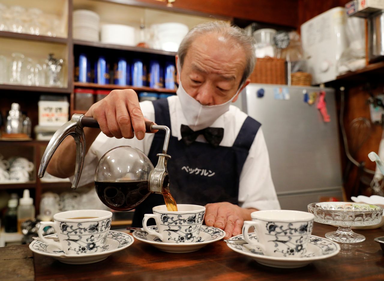  شيزو موري، صاحب مقهى هيكلن، يصب القهوة في فنجان بعد تخمير القهوة باستخدام ماكينة صنع القهوة Siphon في متجره بطوكيو، اليابان، 8 أكتوبر/ تشرين الأول 2021. رويترز / كيم كيونغ هون.