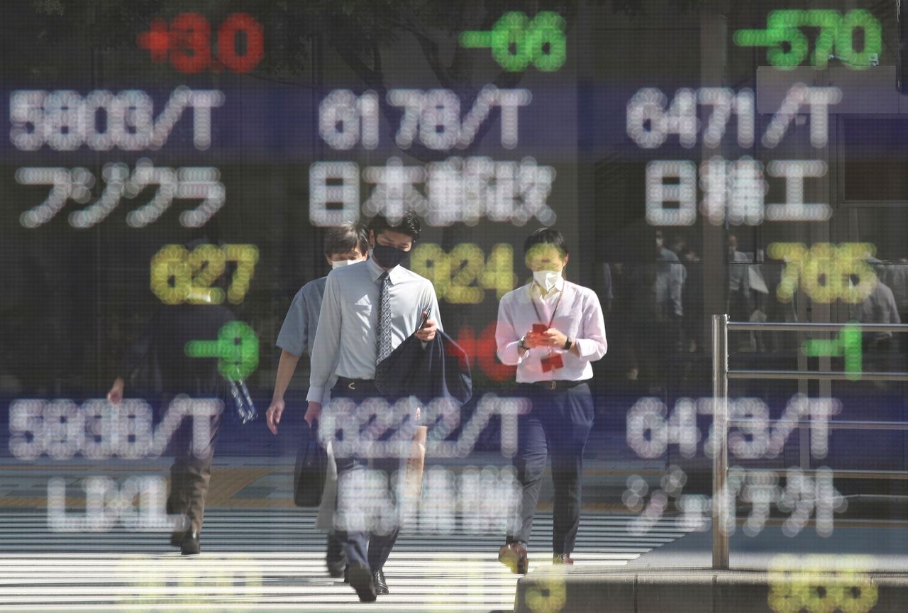 صورة بعض المارة تنعكس على سطح شاشة إلكترونية تعرض حركة المؤشرات خارج بورصة طوكيو في 5 أكتوبر تشرين الأول 2021. رويترز