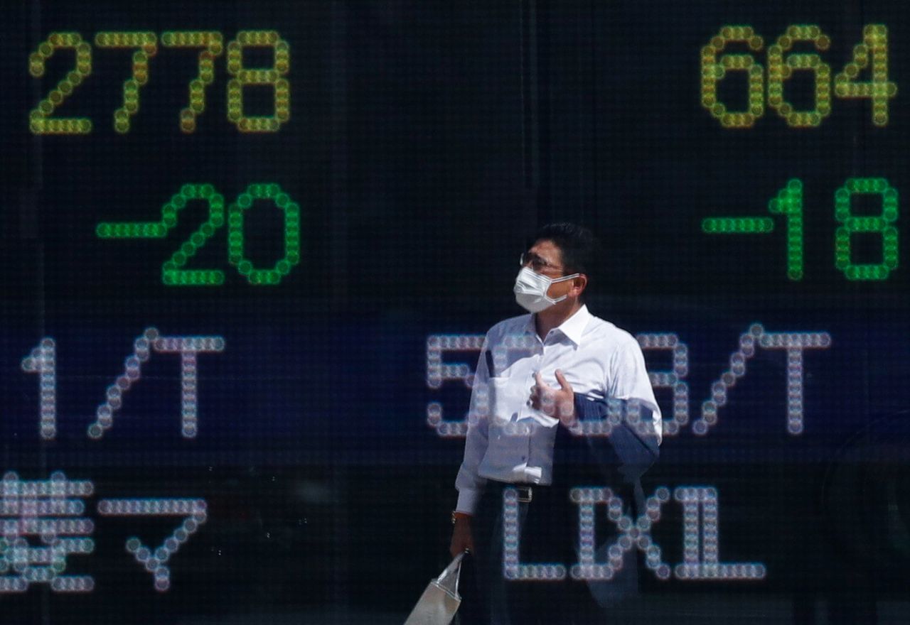 رجل يرتدي كمامة وتنعكس صورته على لوحة إلكترونية تعرض لأسعار الأسهم خارج شركة سمسرة للأوراق المالية في طوكيو يوم 29 سبتمبر أيلول 2021. تصوير:رويترز.