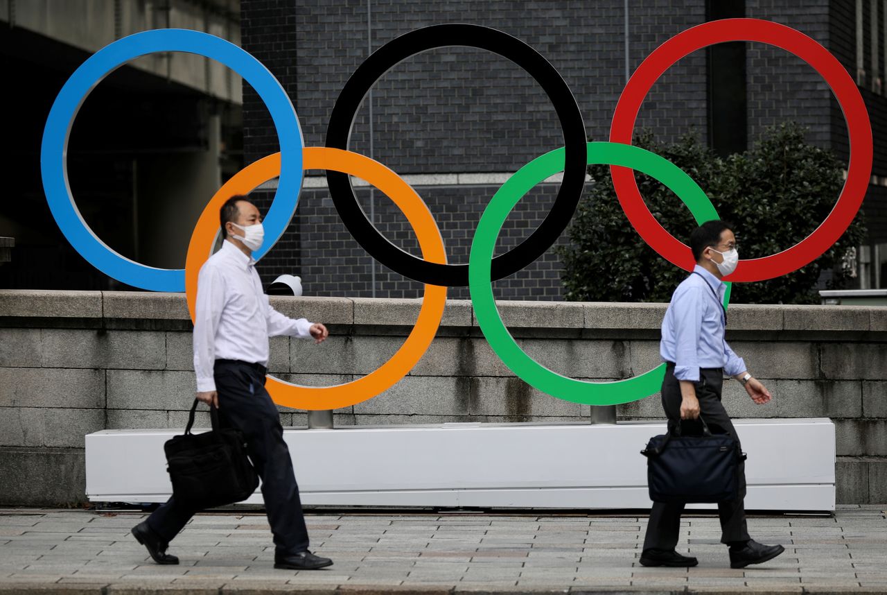 رجال يسيرون بجوار الحلقات الأولمبية في المنطقة التجارية نيهونباشي خلال الألعاب الأولمبية وسط تفشي مرض فيروس كورونا في طوكيو، اليابان، 4 أغسطس/ آب 2021. رويترز / كيفن كومبس. 