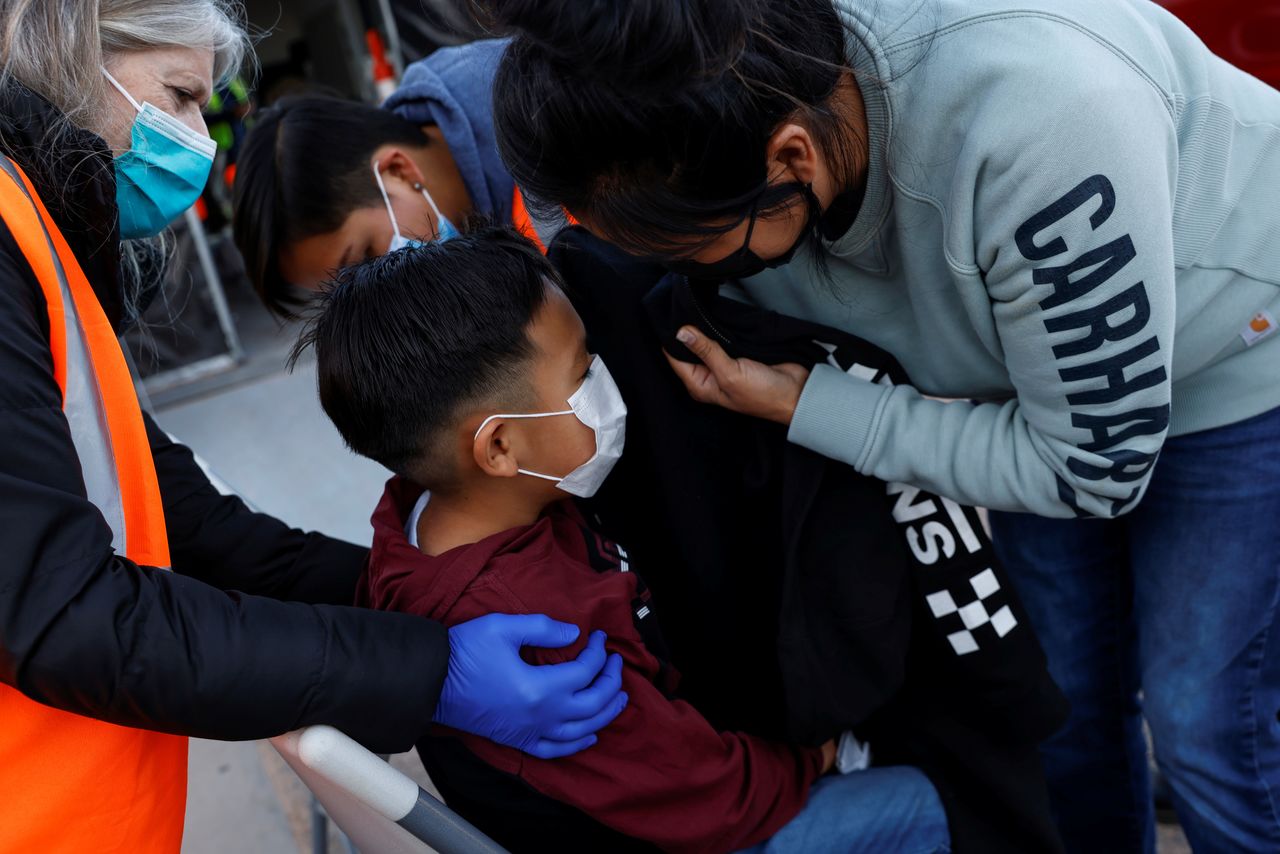 امرأة تغطي عيني ابنها مع تلقيه جرعة منشطة من لقاخ فايزر المضاد لفيروس كورونا في ولاية يوتا الأمريكية يوم الثلاثاء. تصوير:رويترز.