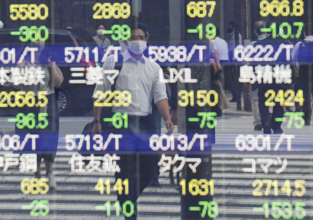 صورة بعض المارة تنعكس على سطح لوحة الكترونية تعرض حركة المؤشرات خارج بورصة طوكيو. رويترز