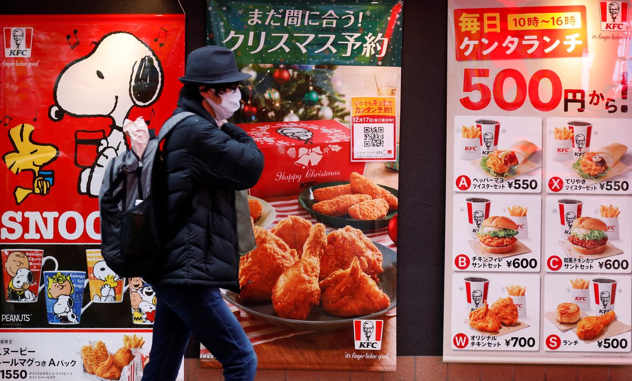 رجل يرتدي قناعًا واقيًا يمر أمام أحد فروع كنتاكي في طوكيو، اليابان، 14 ديسمبر/ كانون الأول، 2021. رويترز / كيم كيونغ هون.