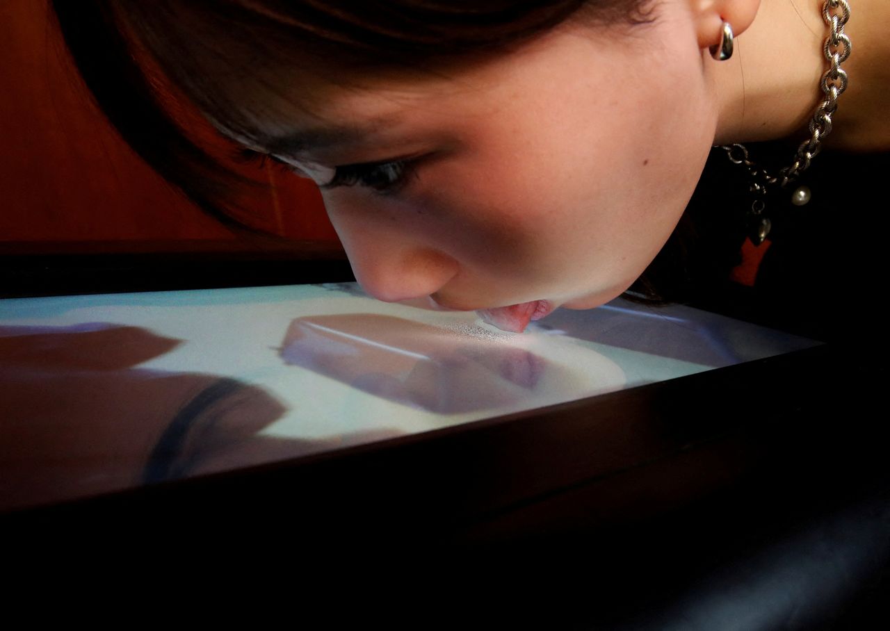 فتاة تجرب شاشة تقدم خاصة التذوق للمشاهدين بطريق اللعق في جامعة بطوكيو يوم 22 ديسمبر كانون الأول 2021. تصوير: كيم كيونج هون - رويترز